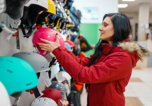 Una mujer con chaqueta roja toma un casco  rosado de un local 