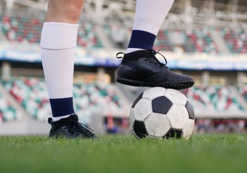 Foto de una persosona con guaybos y un balón de fútbol sobre su pie derecho