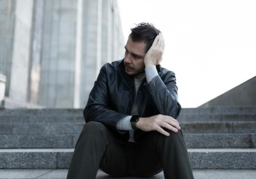 Foto de un hombre sobre una escalera aburrido mirando hacía un costado