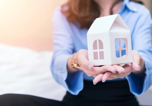 Representación de mujer con una casa en las manos.