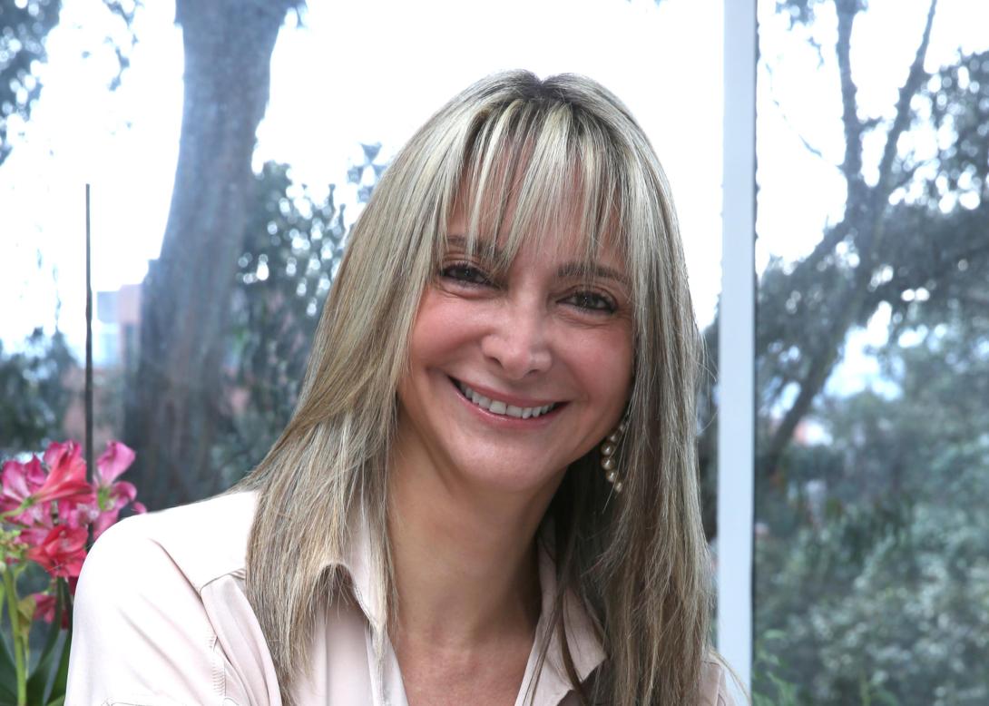 Mujer con cabello rubio sonriendo a la cámara