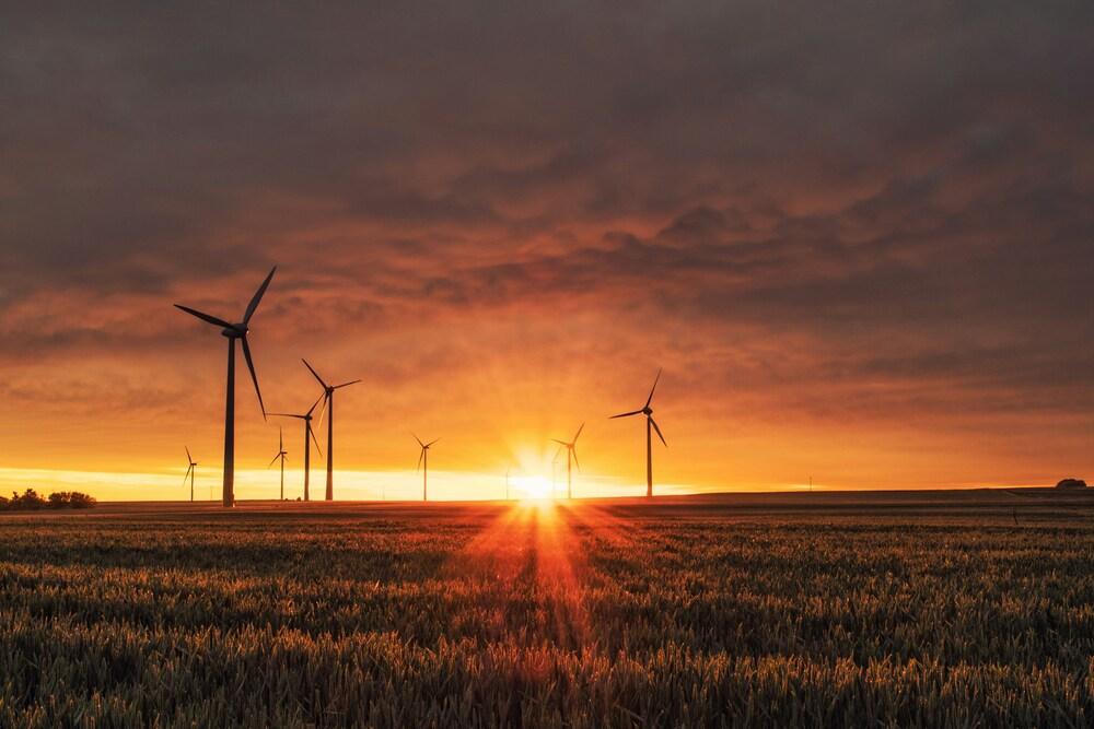 Día de la energia, foto de una puesta de sol con una imagen de energia eólica de fondo