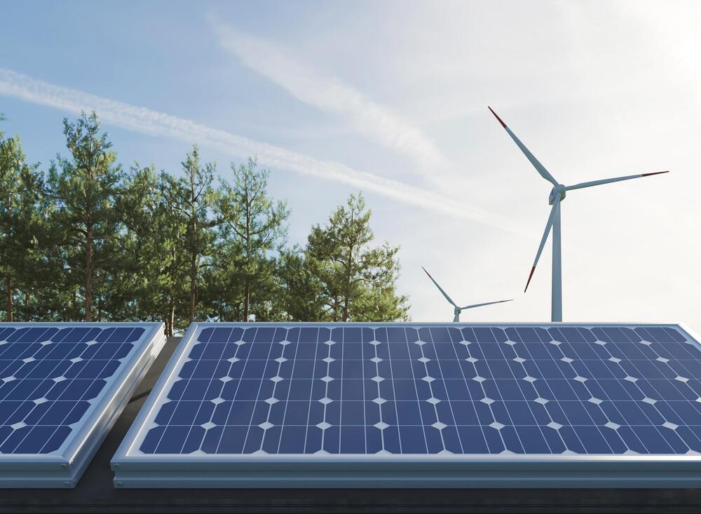 Foto de un panel solar y de fondo una de energía aeólica