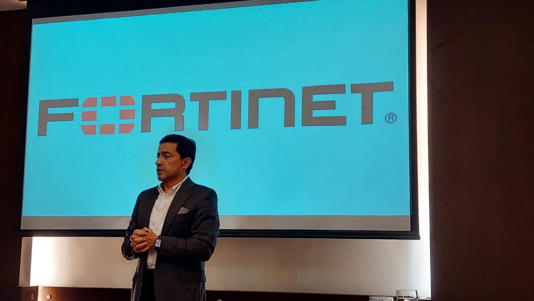 foto de un hombre exponiendo un tema frente a una pantalla que dice Fortinet