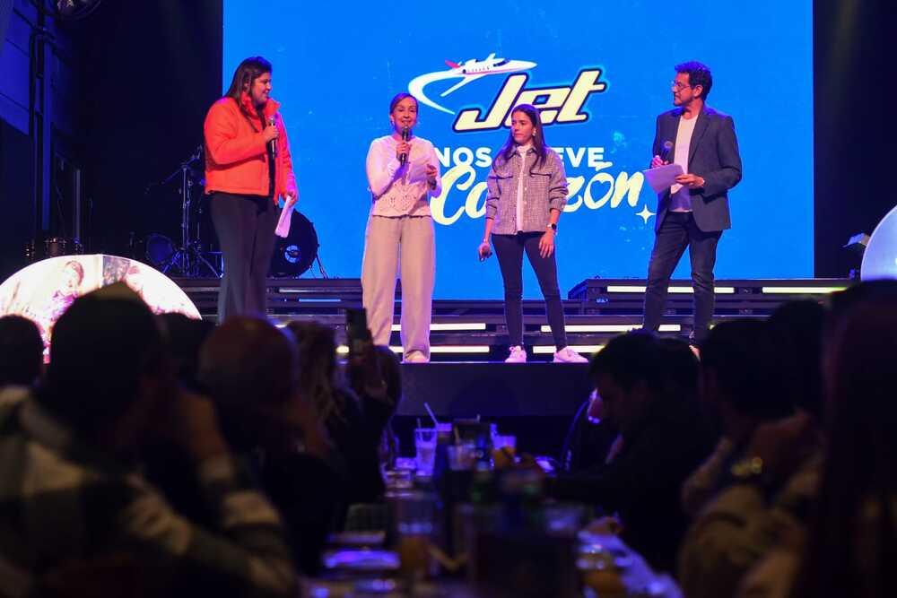 Foto de cuatro personas en un escenario con la marca jet de fondo