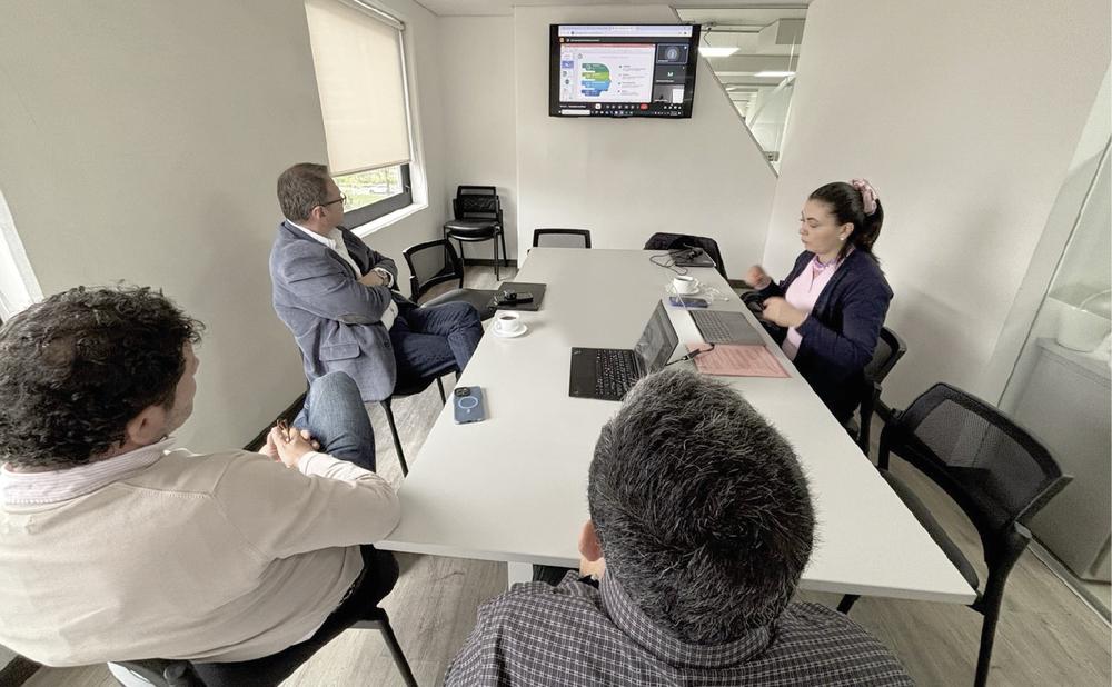 Foto de cuatro personas reunidas en una mesa blanca