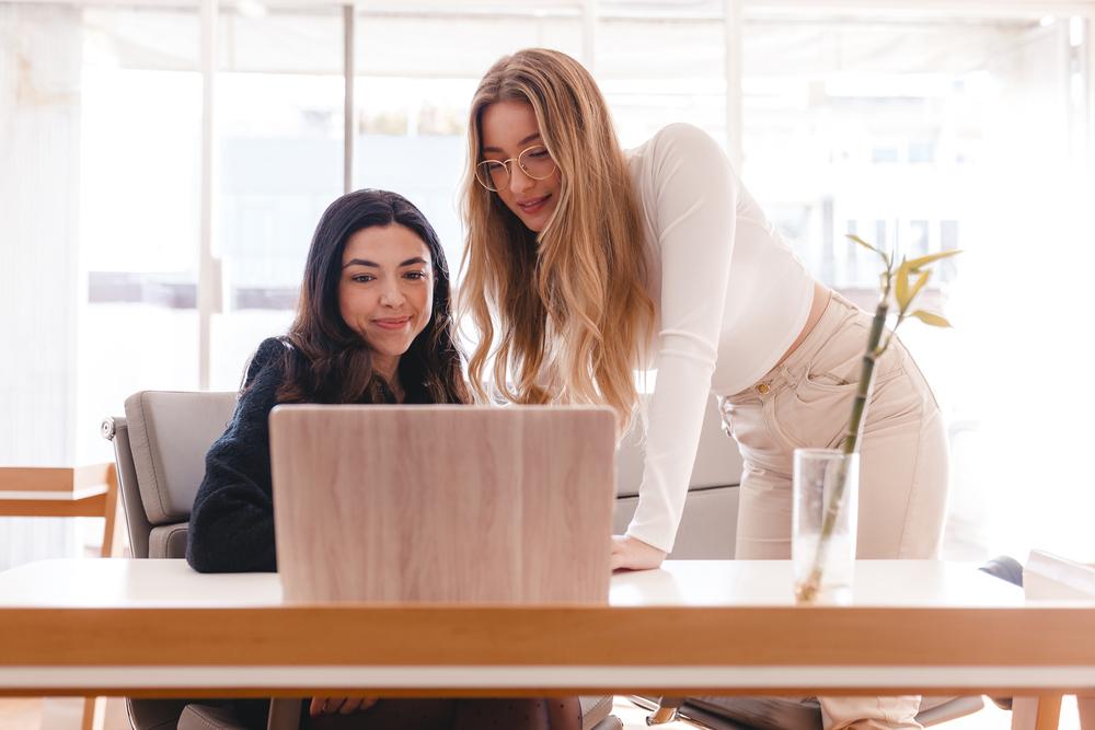 Foto de dos mujeres hablando con una computadora al frente