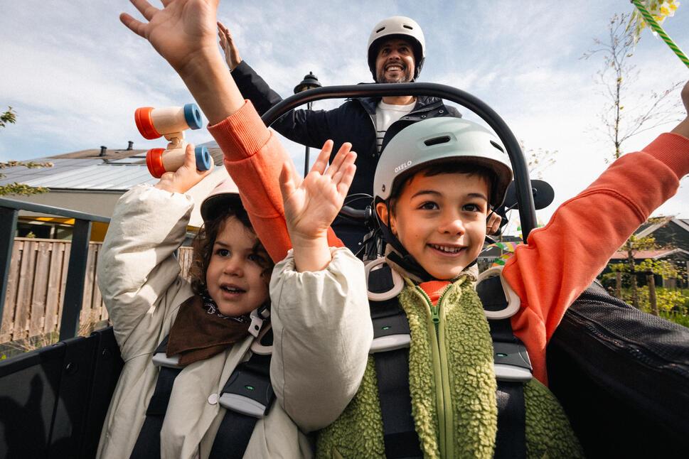 Foto de dos niños disfrutando en una montaña rusa, están alzando las manos