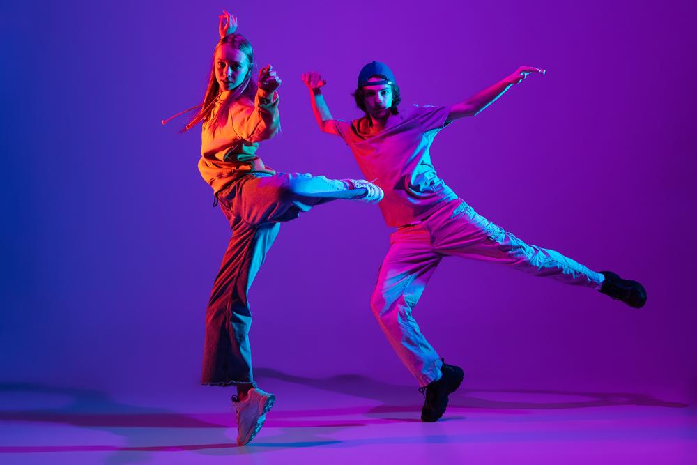 Foto de dos personas bailando con un fondo morado 