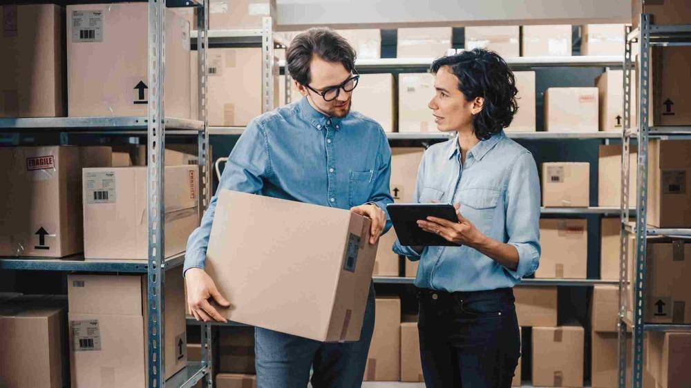 Foto de dos personas hablando con cajas de fondo