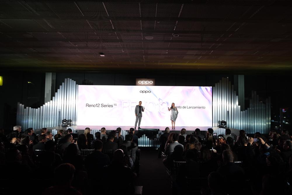 Foto de dos personas presentando frente a una gran pantalla de luz