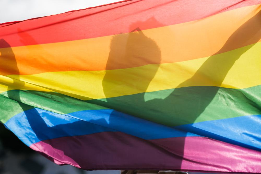 Foto de la silueta de un hombre detrás de una bandera inclusiva