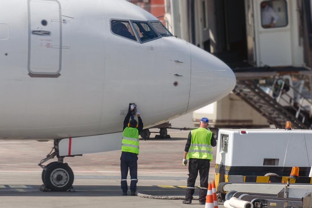 Foto de la trompa de un avión con dos personas debajo 