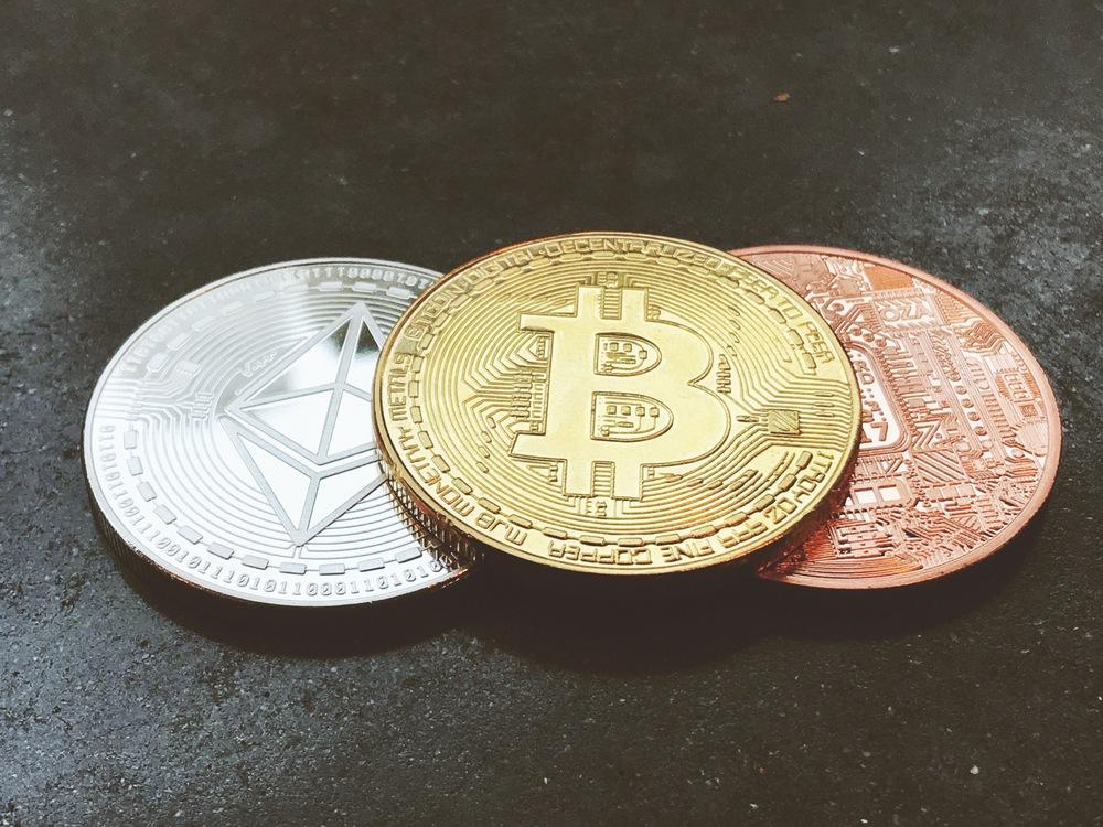 Foto de tres criptomonedas de diferente color