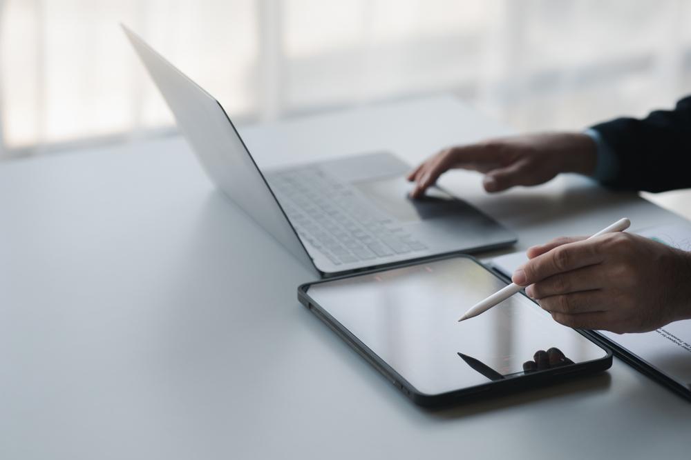 Foto de un empresario con un computador en un lado de la mesa y una tablet en el otro