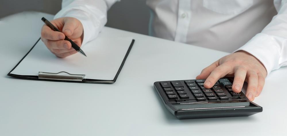 Foto de un hombre con una calculadora y una hoja de papel