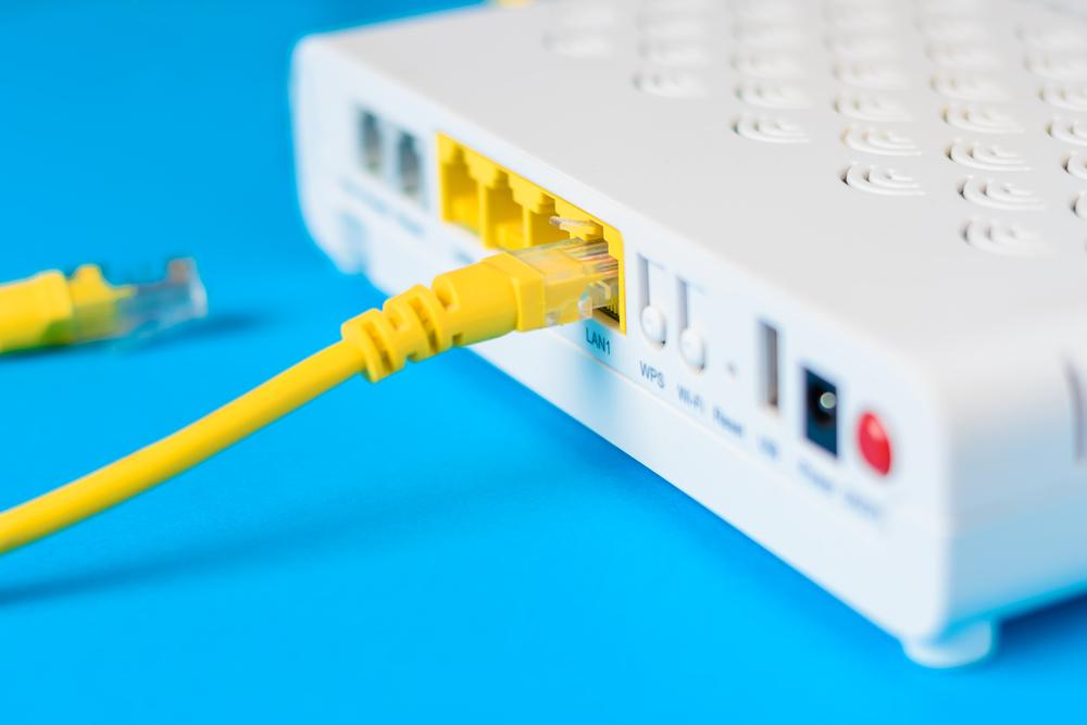 Foto de un modem blanco con cableado amarillo y fondo azul