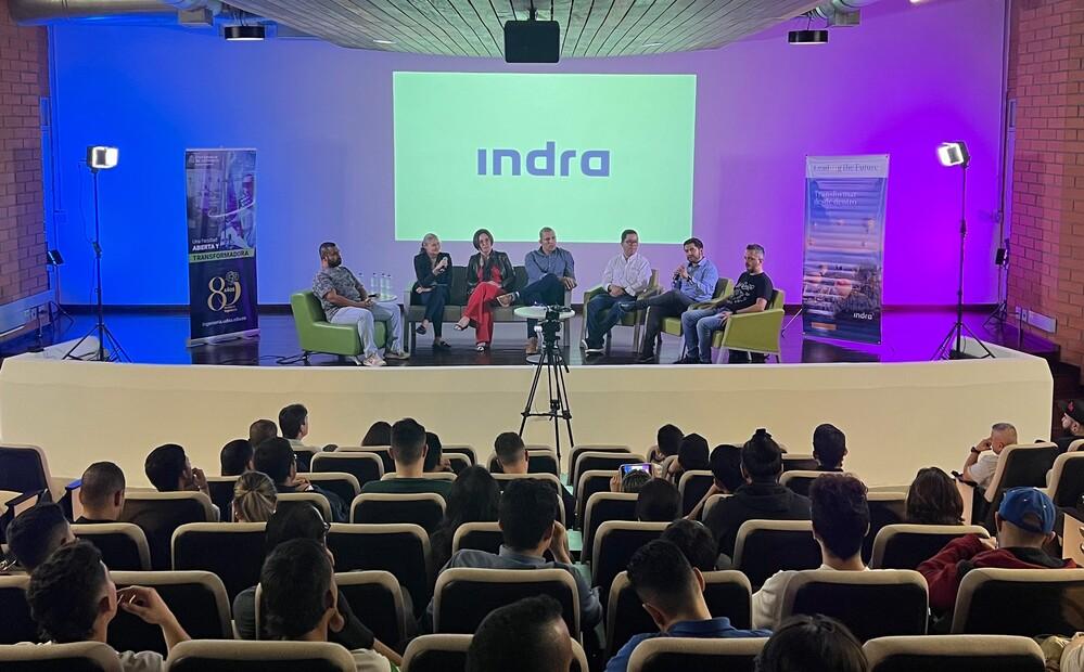 Foto de un panel con varias personas sentadas conversando frente a un auditorio