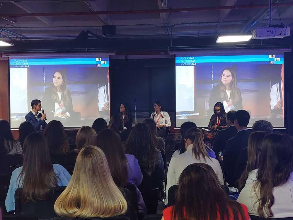 Foto de un salón lleno de personas con mujeres panelistas