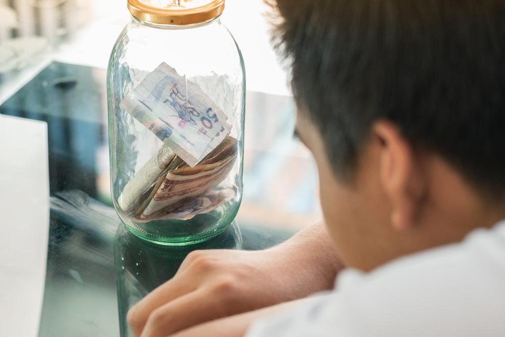 Foto de un señor mirando un frasco con dinero colombiano