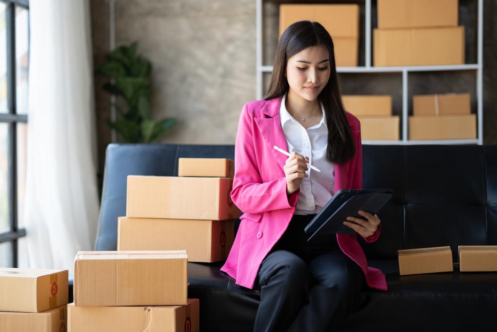 Foto de una mujer con blazer rosado con cajas al fondo