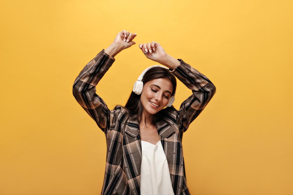 Foto de una mujer escuchando música con un fondo amarillo