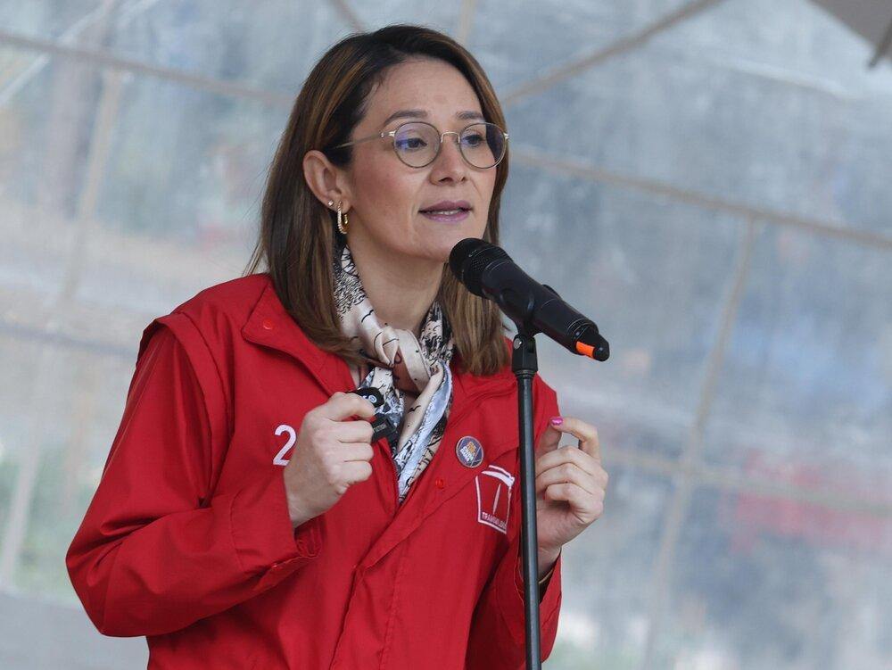 Foto de una mujer hablandole a un microfono con una chaqueta roja