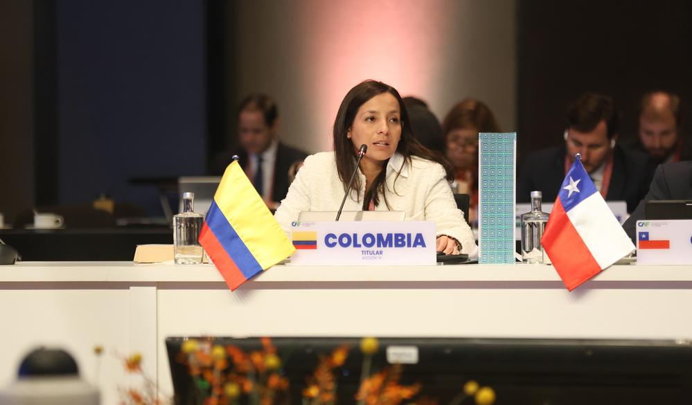 Foto de una mujer sentada en una mesa con banderas de colombia y chile