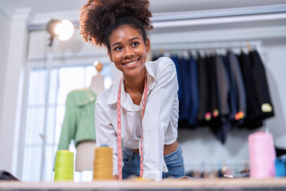 Foto de una mujer sonriendo a la cámara y de fondo unos vestidos