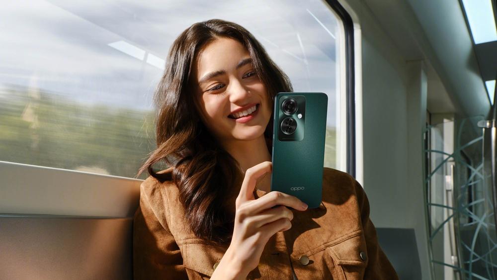 Foto de una mujer sonriendo con un celular verde en la mano