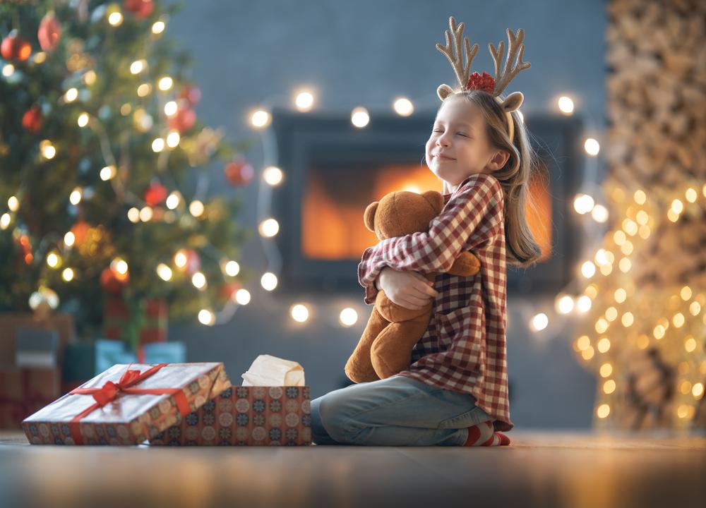 Foto de una niña con un regalo de navidad en sus brazos