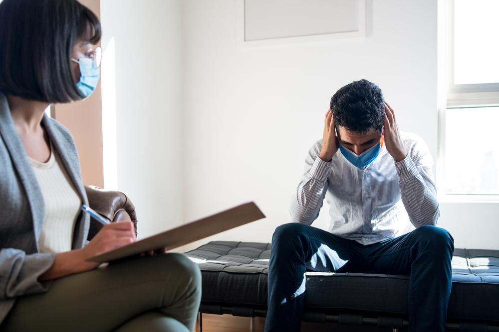 Foto de una persona agarrandose la cabeza en un consultorio