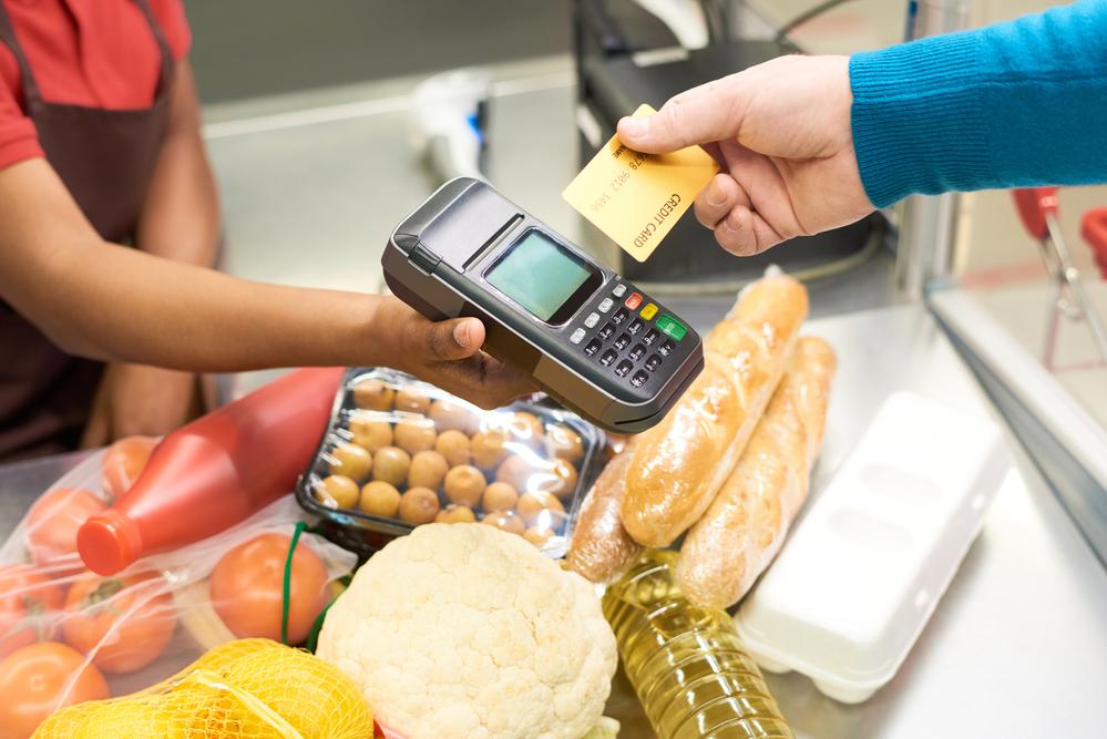 Foto de una persona comprando con una tarjeta mediante un datafono