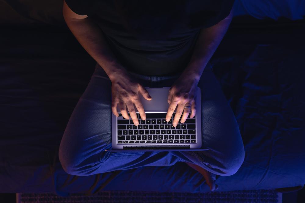 Foto de una persona escribiendo sobre un computador sobre las piernas