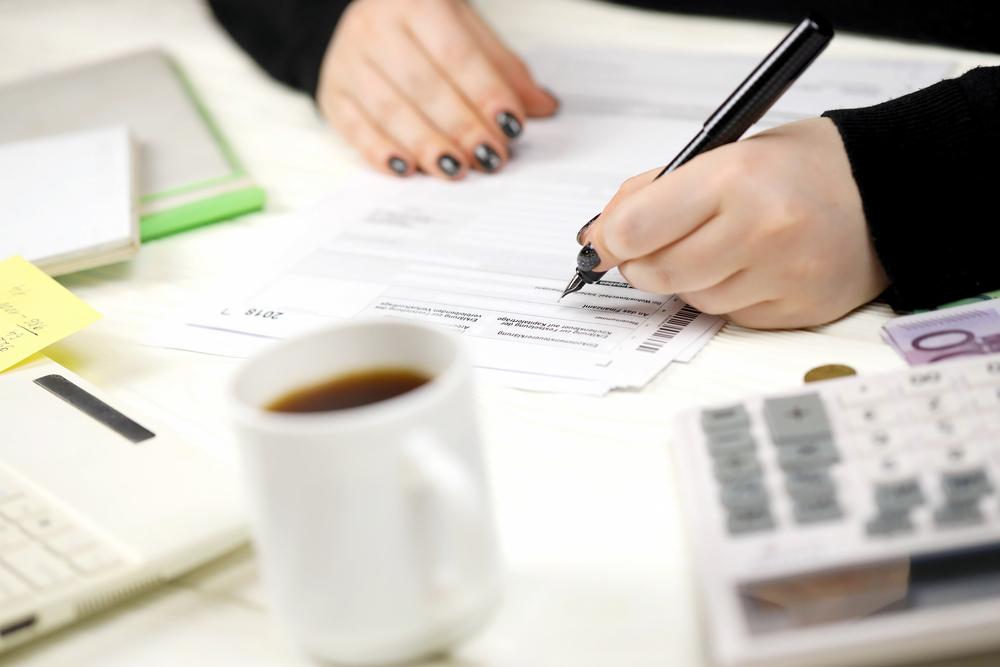 Foto de una persona escribiendo sobre un papel con hojas a su alrededor