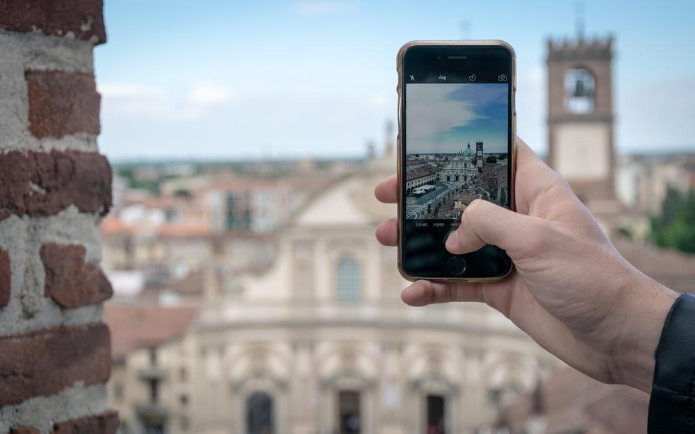 Foto de una persona tomando una fotografia con el celular y el fondo de una ciudad europea