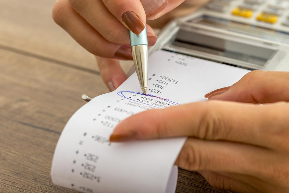 Foto de una persona utilizando un bolígrafo y escribiendo sobre un recibo