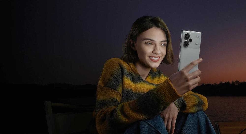 Fotografia de una mujer revisando un celular gris con un atarceder de fondo