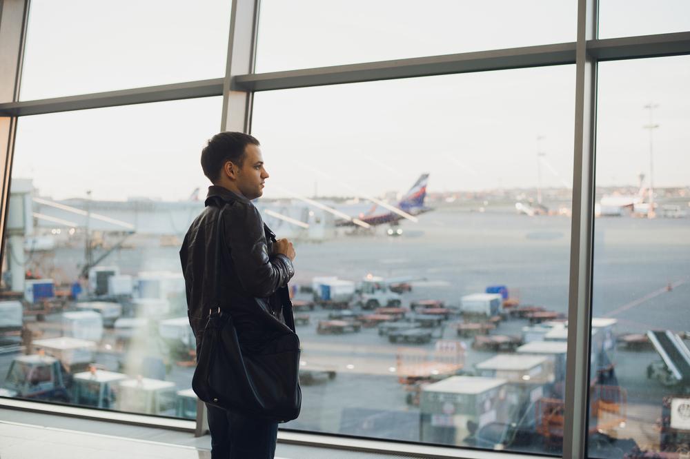 Hombre con traje negro mirando por la ventan de un aeropuerto