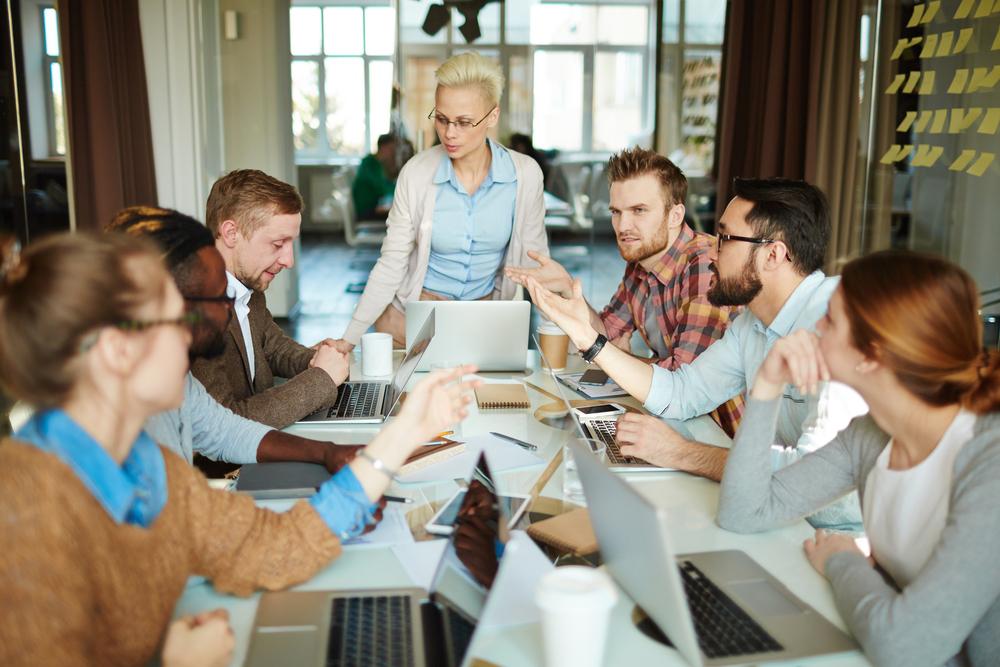 Hombres y mujeres en una mesa compartiendo ideas