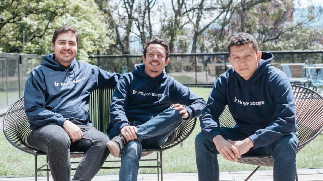 Tres jóvenes sentados, sonriendo a la cámara