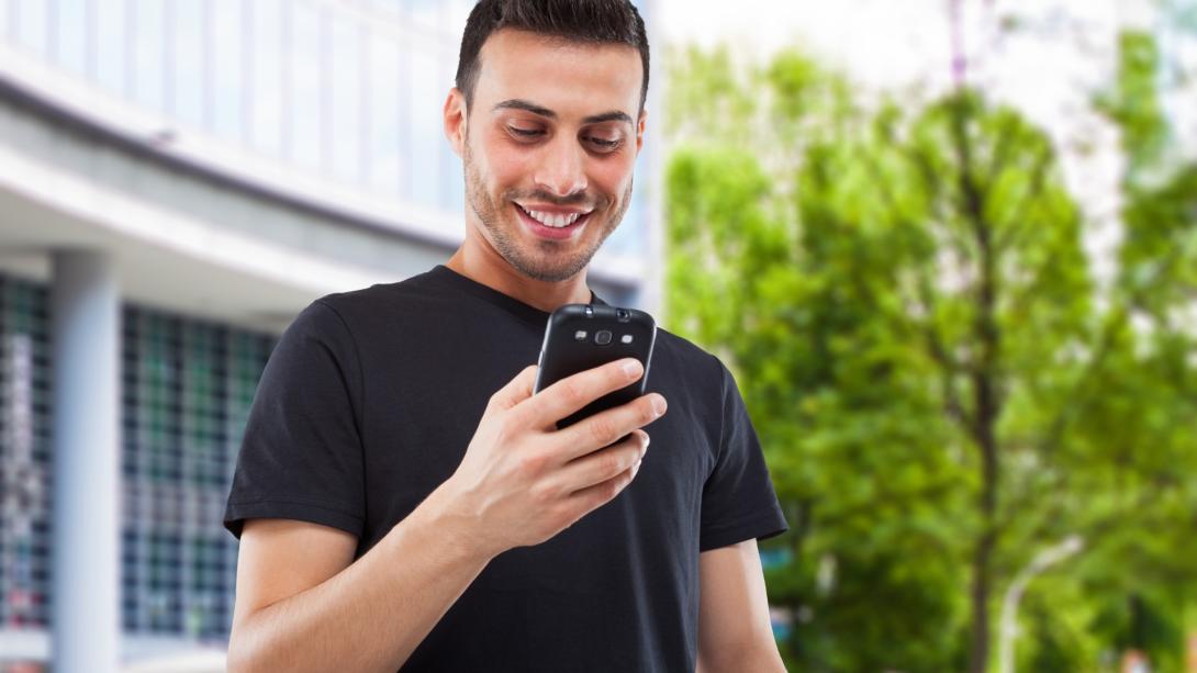 Foto de un hombre mirando al celular mientras sonrie