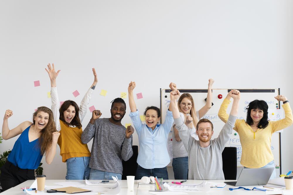 Foto de personas alzando las manos y sonriendo en sus oficinas