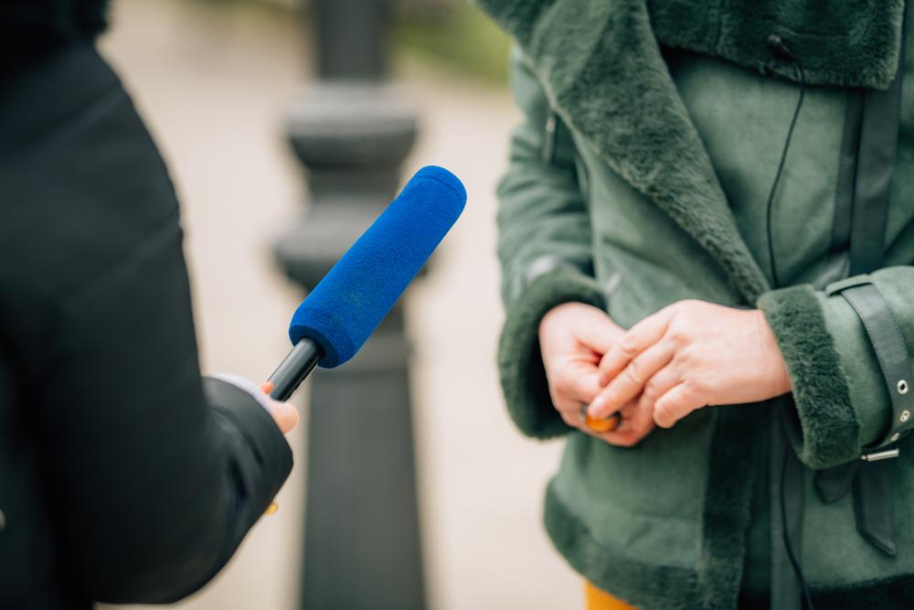 Foto de una persona con un micrófono azul entrevistando