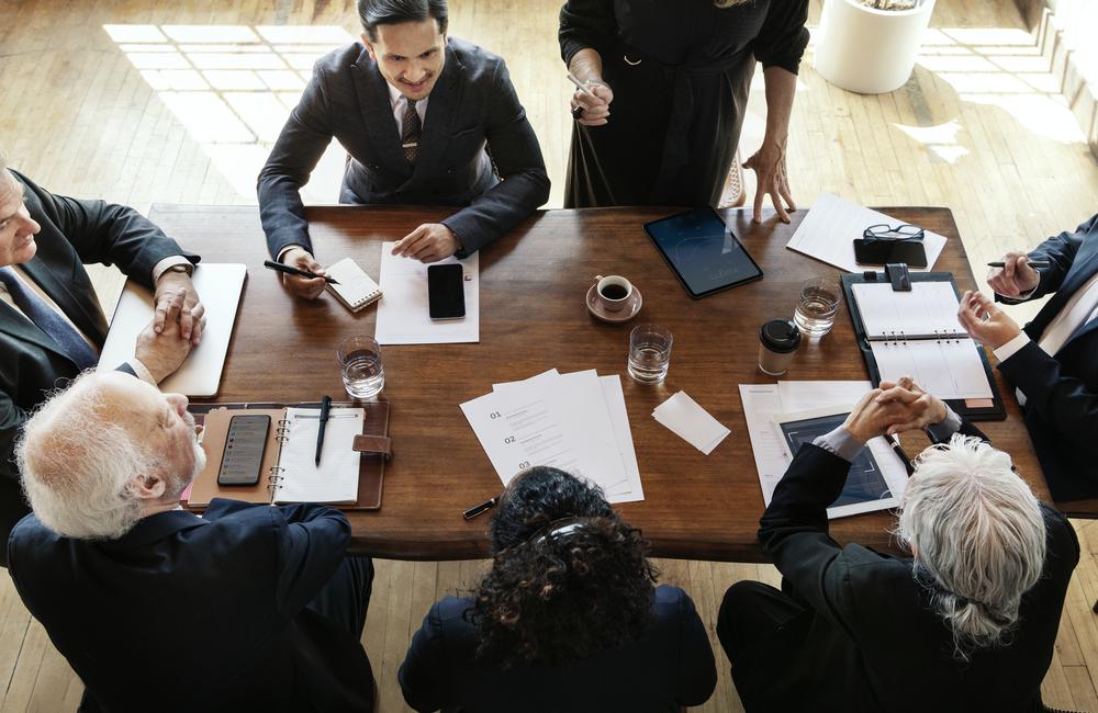 Una foto cenital de varias personas ejecutivas sentadas en una mesa