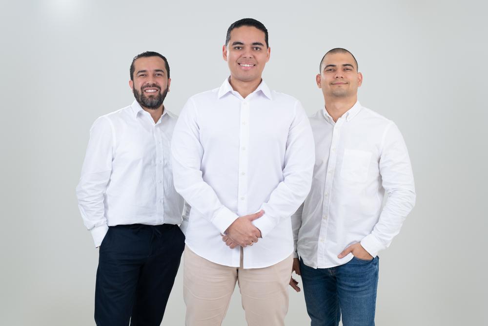 Fotografía de tres hombres con camiseta blanca mirando a la cámara