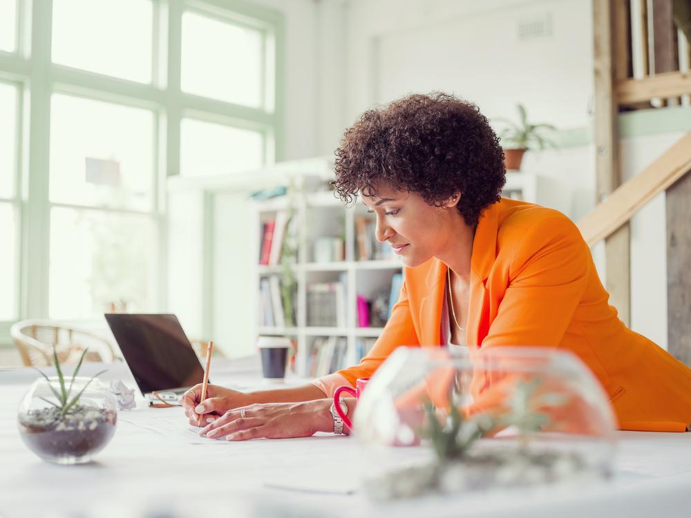 Mujer con blazer naranja mirando el computador