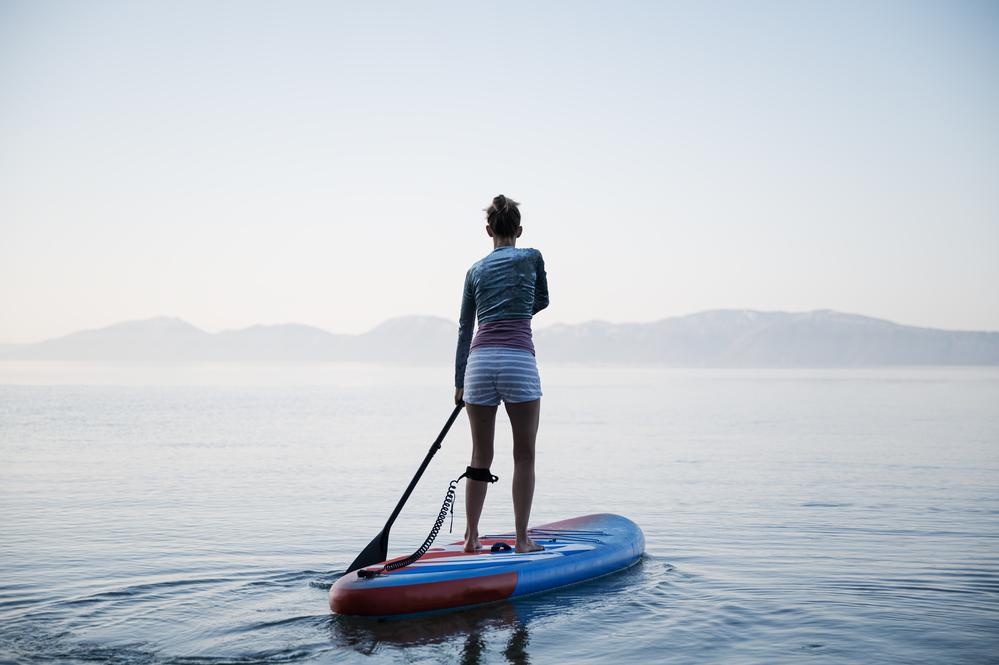 Mujer encima de una tabla en un lago