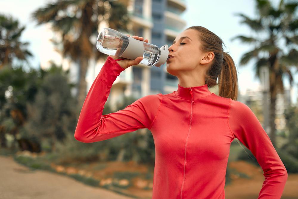 Mujer tomando agua de un termo