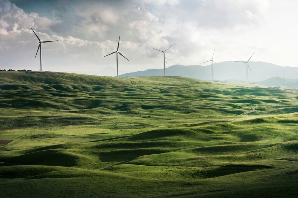 Paisaje de unas montañas y al fondo medios de propulsión de energía eólica